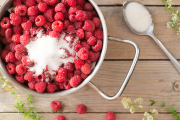 Pan with raspberry and sugar on wooden table