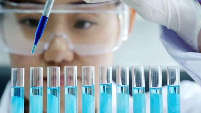 Scientist with a pipette analyzes a colored liquid in the test tubes. People with science concept. 4K Resolution.