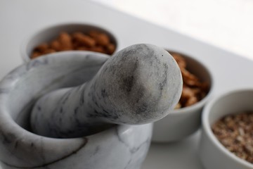 Marble Mortar and near it two white pottery containers with almonds and walnuts