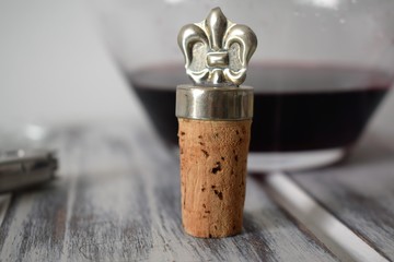 Cork and buckler over a wooden table with a decanter with red wine over it