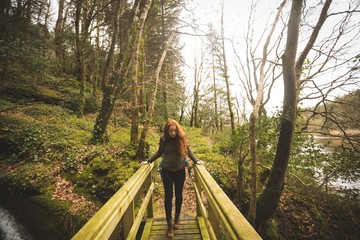 Female hiker walking on bridge in the forest
