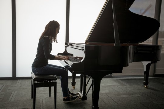 Schoolgirl playing piano in music school