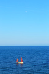 Red sailing boats on the sea with moon in background