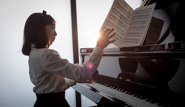 Schoolgirl playing piano in music school