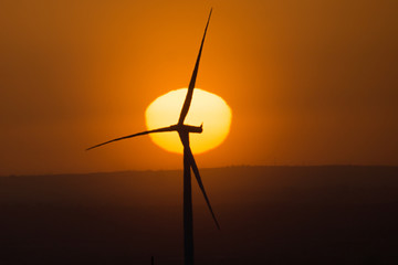 Fototapeta na wymiar Wind turbines against a background of sunset and orange sky 