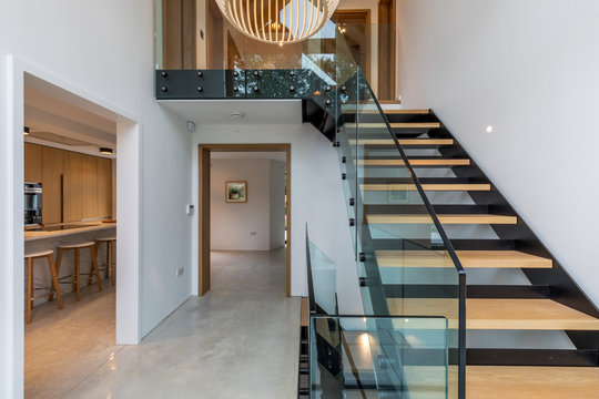 Entrance hall of a modern house with views of staircase, kitchen and hall.