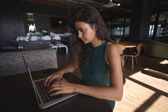 Businesswoman using laptop at office cafeteria