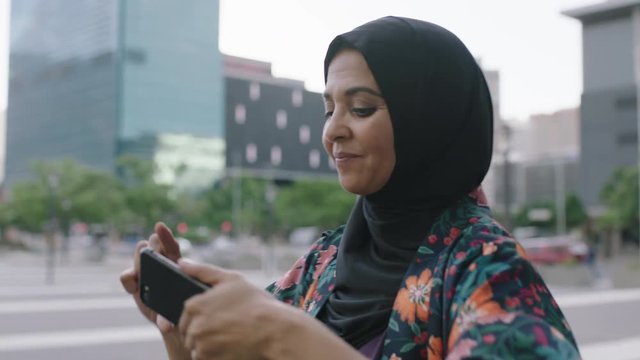 portrait of elegant mature muslim woman taking photo using smartphone camera technology wearing traditional headscarf in urban city background