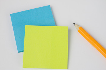 Pencil and sticky notes on a white table. Office accessories for saving notes.