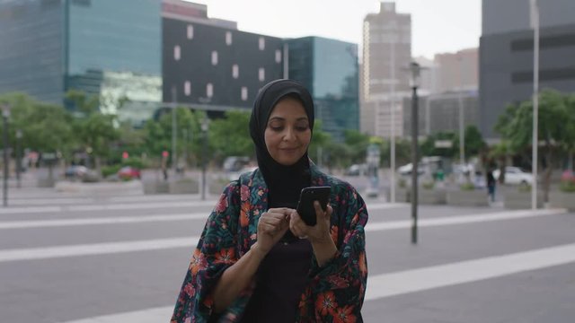 portrait of elegant mature muslim woman texting browsing using smartphone social media app enjoying chatting in sunset urban city background