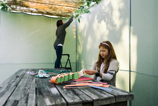 Sukkot: Girl Sits In Sukkah Making Decorations With Paper