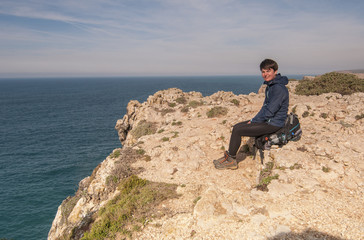 Fototapeta na wymiar The girl is seating on the coast of the Atlantic ocean, cliffs, Portugal