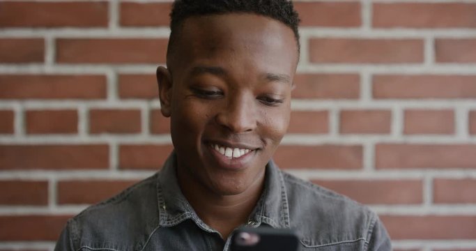 portrait young african american man student using smartphone smiling enjoying texting browsing online reading sms messages on mobile phone