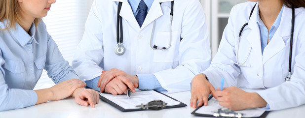 Doctors and patient talking while sitting at the table . Concept of support and trust in medicine