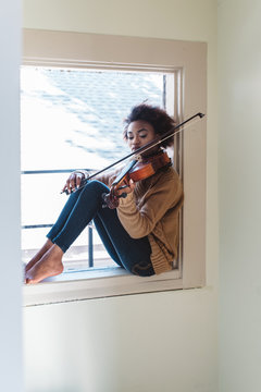 A young woman playing the viola at home