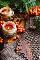 Autumn composition and candles and needles on  textured sweater on wooden background  .  Autumn or Winter concept.