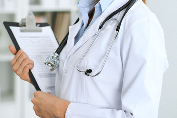 Closeup of unknown doctor woman standing with medication history records form at hospital.  Health care, insurance and help concept