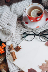 Stylish Flat lay view of autumn leaves and tartan textured sweater on wooden background with cup of tea .  Autumn or Winter concept. 