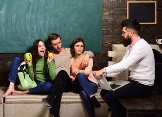 College and university concept. Students, scientists studying , professor holds laptop, teaches, explains, chalkboard background. Group of students, group mates listening teacher, lecturer, professor