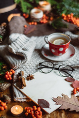 Stylish Flat lay view of autumn leaves and tartan textured sweater on wooden background with cup of tea .  Autumn or Winter concept. 