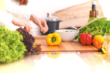 Close Up of human hands cooking vegetable salad in kitchen on the glass table with reflection. Healthy meal, and vegetarian food concept