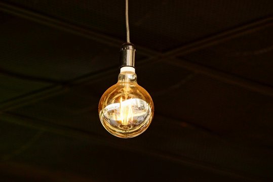 large luminous round light bulb on a cord in a dark room