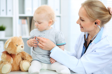 Doctor and patient in hospital. Little girl is being examined by pediatrician with stethoscope....