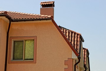 part of a private brown house with a window under a roof against the sky