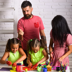 Girls drawing with mother and father. Happy childhood and parenting. Imagination, creativity concept. Finger painting and arts. Children playing and learning with parents.