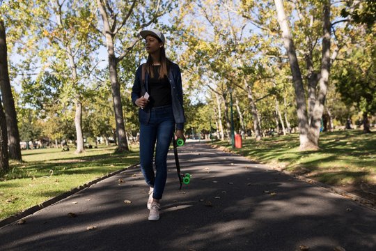 Woman walking in the park with skateboard