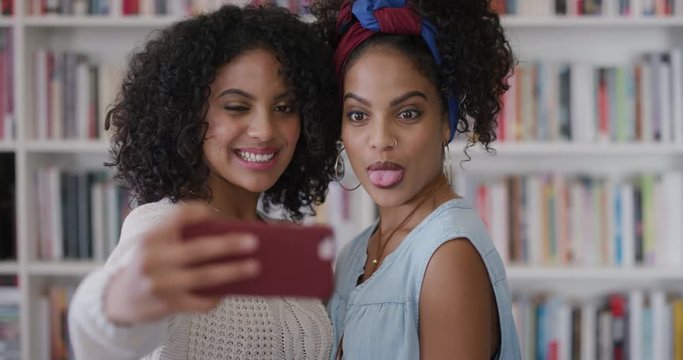 portrait beautiful hispanic twin sisters using smartphone taking selfie photo posing making faces enjoying fun together smiling happy mobile phone camera technology