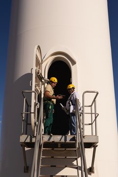 Engineers standing at the entrance of wind mill
