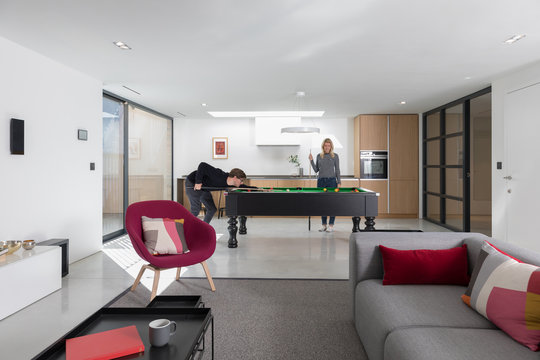 Couple playing a game of pool inside their spacious modern apartment.