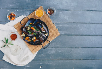 Mussels in white wine sauce over wooden background. Top view, copy space