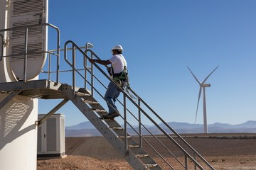 Engineer climbing up the stairs of a wind mill