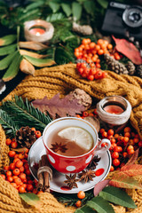  Flat lay view of autumn leaves,candles  and textured scarf on wooden background with cup of tea . Autumn or Winter concept.