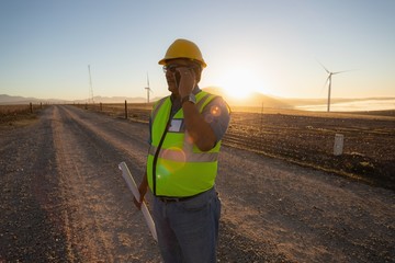 Engineer talking on mobile phone at wind farm