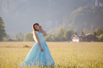 Fototapeta premium blond girl in blue dress infront of the castle