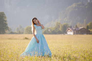 blond girl in blue dress infront of the castle