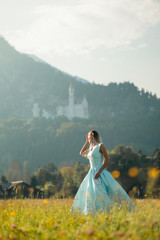Blond girl in blue dress infront of the castle