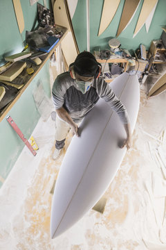 Male surfboard shaper working in his workshop