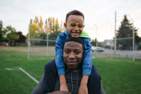 Man and child enjoying shoulder ride together outside in field