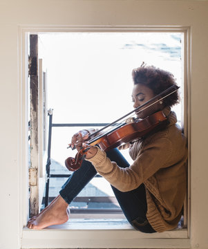 A young woman playing the viola at home