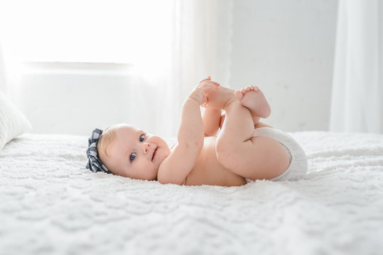 Cute Baby Smiling And Grabbing Her Toes