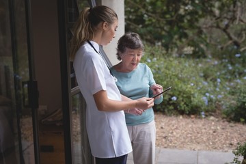 Physiotherapist and senior woman using a tablet