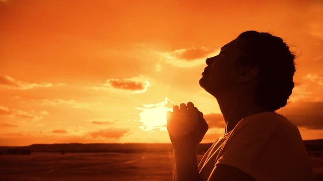 the girl prays. Girl folded her hands in prayer silhouette at sunset. lifestyle slow motion video. Girl folded her hands in prayer pray to God. girl praying asks forgiveness for sins of repentance