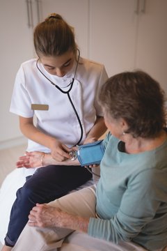 Physiotherapist checking blood pressure of senior woman