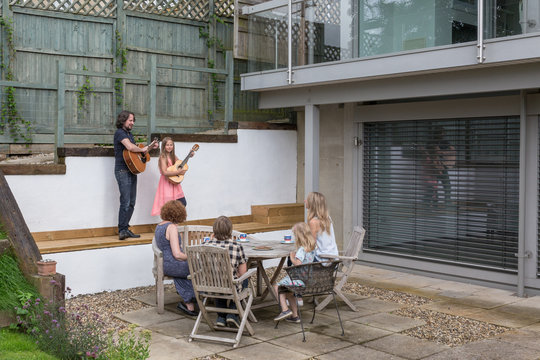 Impromptu musical performance by father and daughter in the patio area of their modern house.