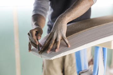 Male surfboard shaper marking stringer on foam