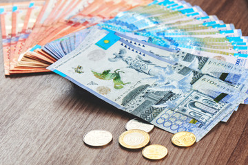 Tenge. Kazakh money is spread out on a brown wooden table close-up..
